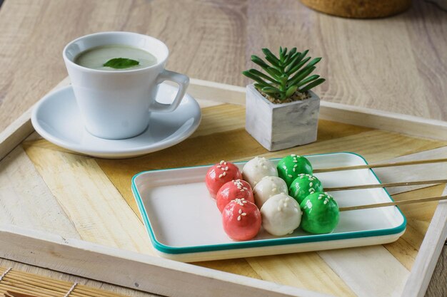 Sanshoku Dango três bolinhos coloridos com chá matcha servido na mesa de madeira