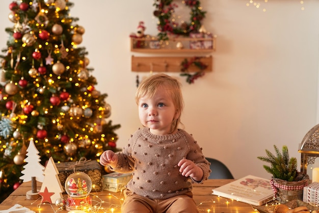 Santa Baby Weihnachtsbaum Hintergrund Frohes neues Jahr Kind im Strickanzug