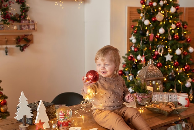 Santa bebé árbol de Navidad fondo feliz año nuevo niño en traje de punto