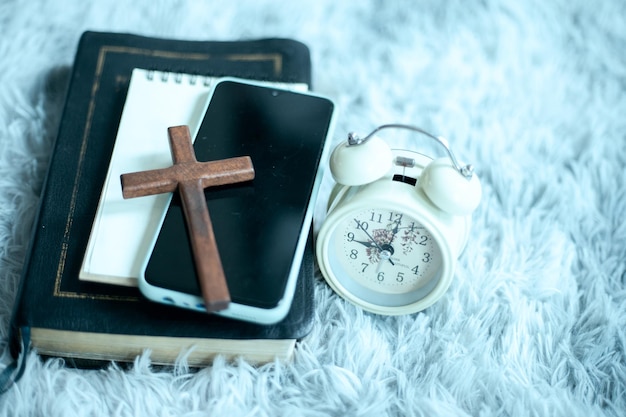 Santa biblia con auriculares smartphone y cruz de madera.