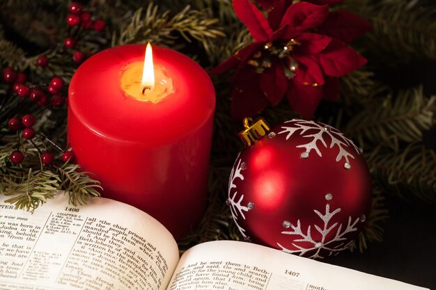 Santa Biblia con una gran vela roja y adornos navideños