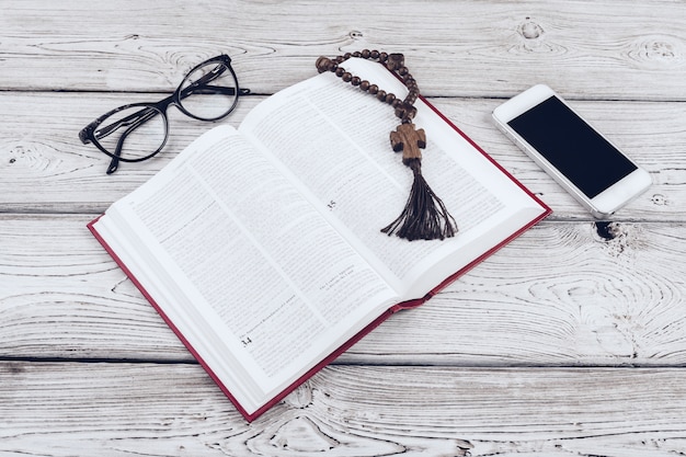 Santa Biblia y smartphone con taza de café negro en la superficie de madera.