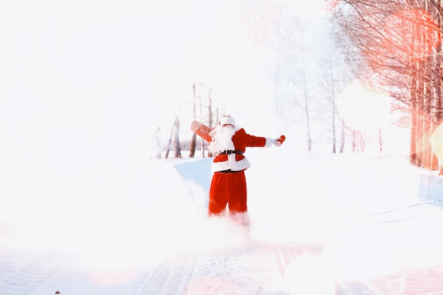 Santa en el campo de invierno. Santa niebla mágica caminando por el campo. Santa en Nochebuena lleva regalos a los niños en una bolsa roja