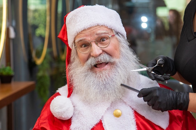 Santa Claus afeitado en peluquería. Preparándose para la Navidad. Embellecimiento para las vacaciones. Barbado. Cortando.