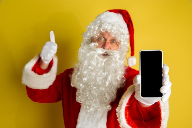 Santa Claus con anteojos modernos aislado sobre fondo amarillo studio