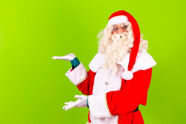 Foto santa claus apuntando hacia el lado con espacio para texto santa claus sobre fondo verde apuntando al espacio libre para texto