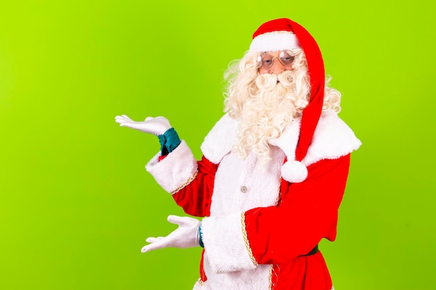 Foto santa claus apuntando hacia el lado con espacio para texto santa claus sobre fondo verde apuntando al espacio libre para texto