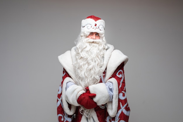 Santa Claus apuntando con la mano en el espacio vacío sobre fondo gris de estudio con espacio de copia para publicidad de año nuevo de Navidad. Foto de alta calidad