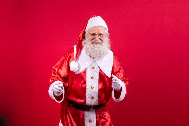 Santa Claus bailando feliz sobre fondo rojo.