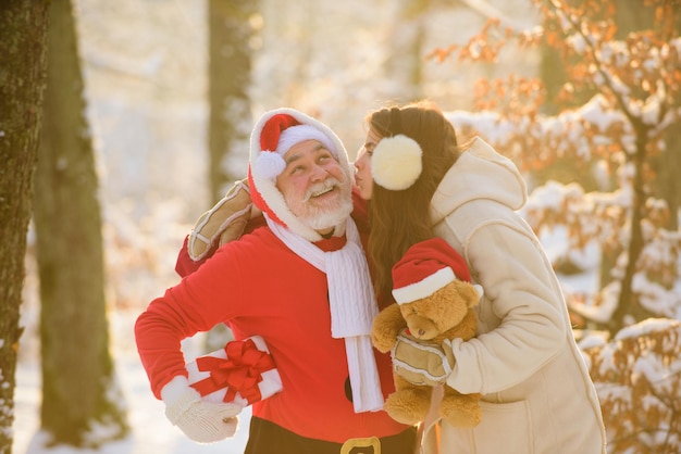 Santa claus besa a una mujer navidad y año nuevo santa claus con niña besándose al aire libre en la nieve