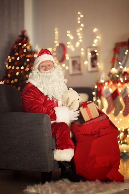 Santa Claus con bolsa de regalo en habitación decorada para Navidad