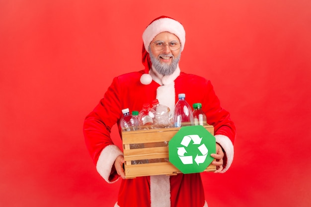 Santa claus con caja de madera con botellas de plástico y signo de reciclaje.