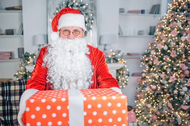 Santa Claus con una caja de regalo cerca de un árbol de Navidad