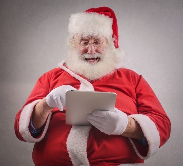 Santa Claus, die eine Tablette verwendet