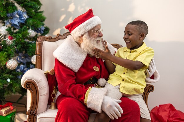 Santa Claus, die einem kleinen afrikanischen Jungen eine Geschenkbox liefert