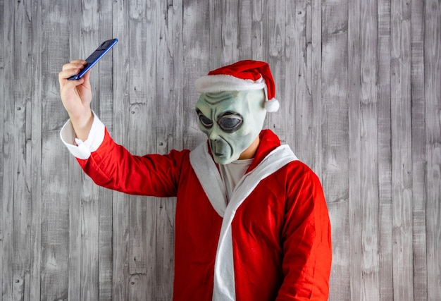 Santa Claus disfrazado de alienígena tomando un selfie