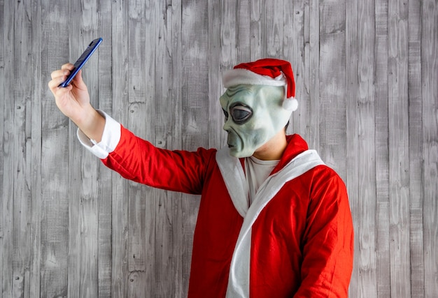 Santa Claus disfrazado de alienígena tomando un selfie