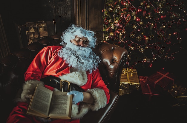 Santa claus durmiendo con el libro en las manos