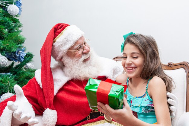 Santa Claus entregando una caja de regalo a una niña