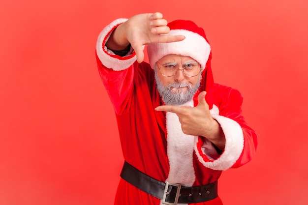 Santa claus gesticulando el marco de la imagen con las manos, mirando y centrándose en un momento interesante