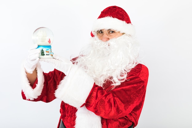 Santa Claus con un globo de nieve de Navidad en sus manos, sobre fondo blanco.