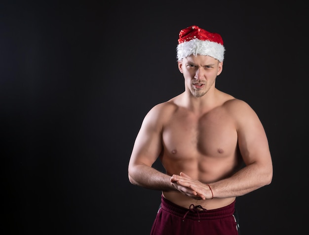 Santa Claus con gorra atleta de fitness desnudo malvado le da la mano en la oscuridad