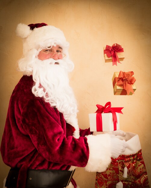 Santa Claus haciendo malabares con cajas de regalo de Navidad. Concepto de vacaciones de Navidad