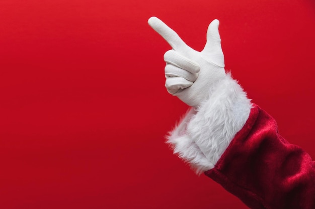 Santa Claus-Hand, die Finger gegen einen roten Hintergrund zeigt