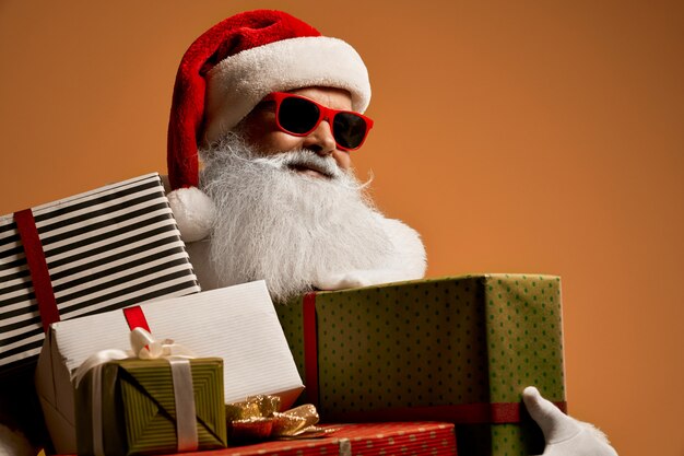 Santa Claus in der roten Sonnenbrille mit den Geschenkboxen, die weg schauen