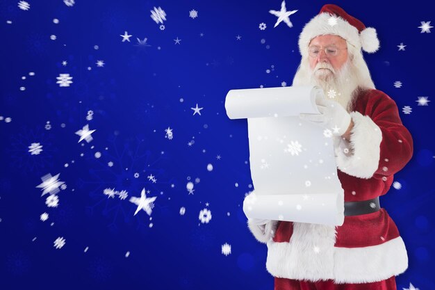 Santa Claus lee una lista contra el fondo azul del copo de nieve