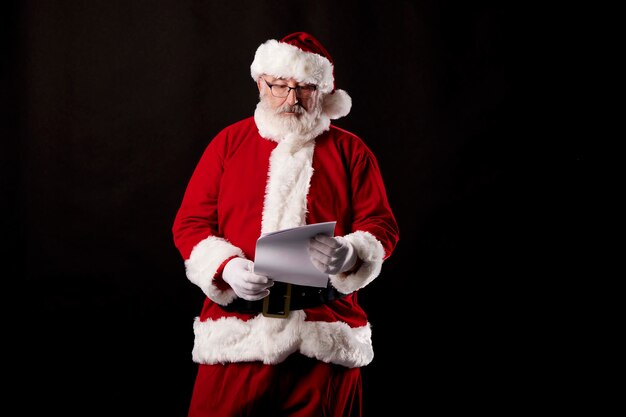 Santa Claus leyendo una carta sobre fondo negro