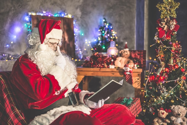 Santa claus leyó un libro por la noche en la casaLa luz del libroUsando la luz de la sala de la linterna