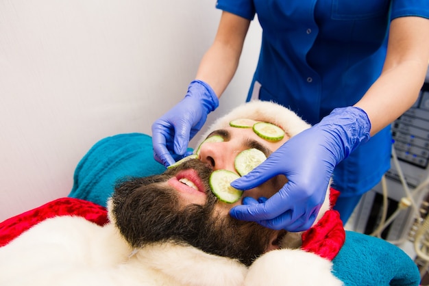 Santa Claus con mascarilla de pepino en el spa de belleza