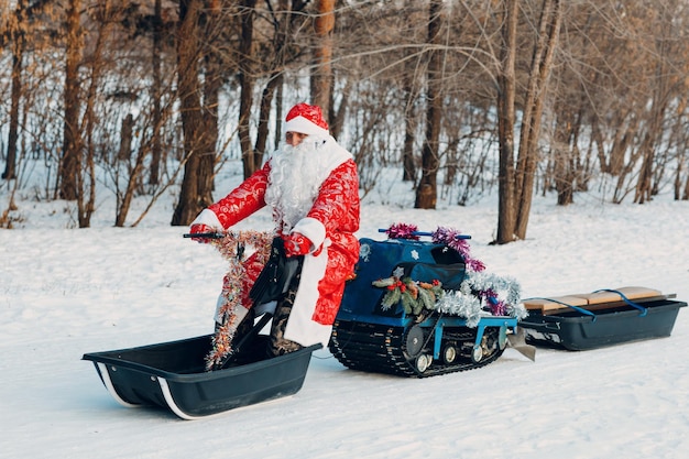 Santa claus montando motos de nieve en el bosque de invierno.