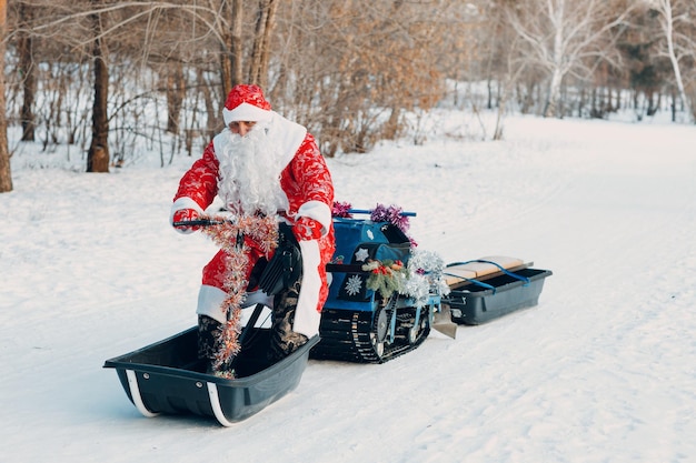 Santa claus montando motos de nieve en el bosque de invierno.