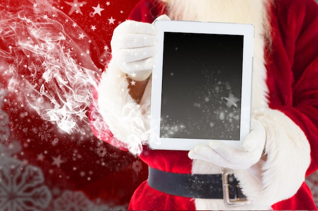 Santa claus mostrando tablet pc contra el marco de Navidad borrosa