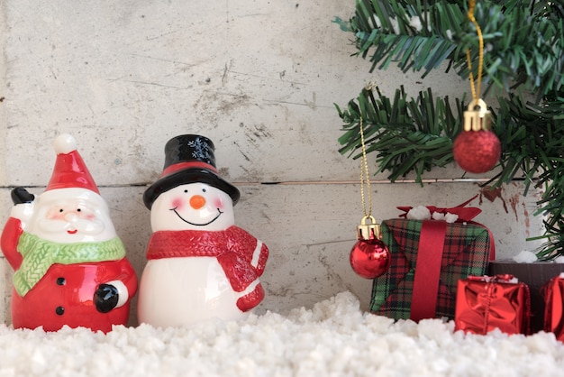 santa claus y muñeco de nieve en la nieve con el árbol de navidad en el fondo de la vendimia