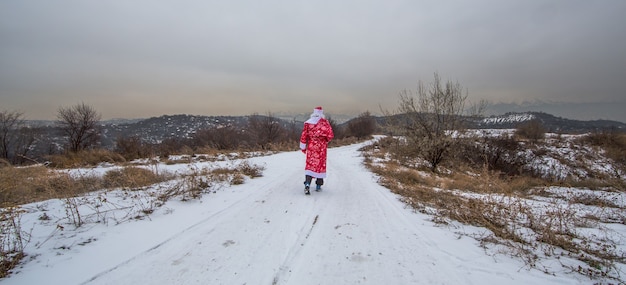 Santa Claus va en un paisaje invernal de carretera nevada