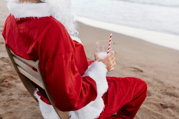 Santa claus en la playa con bebida ángulo alto