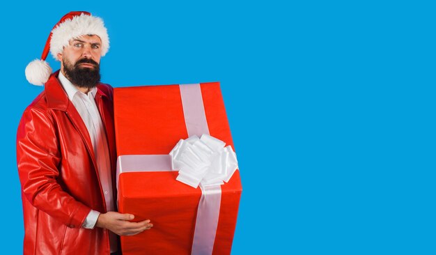 Santa Claus con presente. Tiempo de Navidad. Hombre barbudo con gorro de Papá Noel con caja de regalo. Publicidad de año nuevo. Copie el espacio.