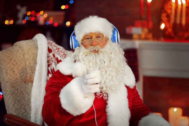 Santa Claus sentado con auriculares sentado en una cómoda mecedora en casa