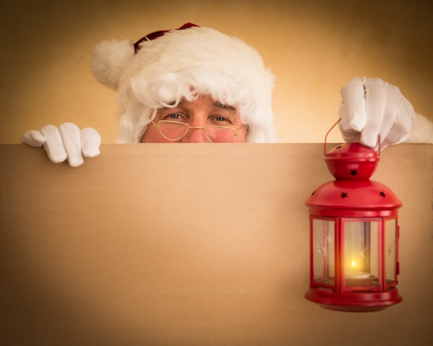 Santa Claus sosteniendo linterna mágica y banner en blanco. Concepto de vacaciones de Navidad