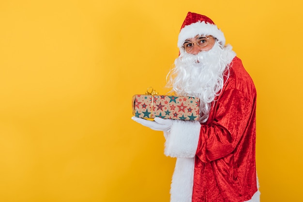 Santa Claus sostiene un regalo en amarillo