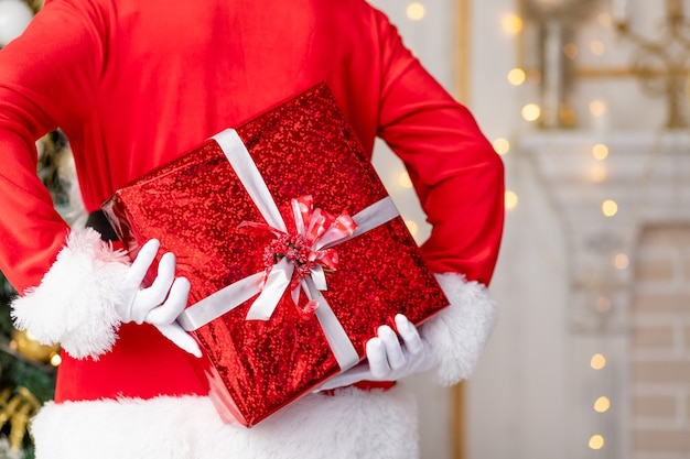 Santa Claus sostiene un regalo en un paquete rojo a la espalda