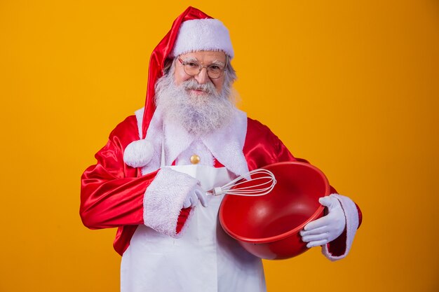 Santa Claus con un tazón batiendo la torta sobre fondo amarillo