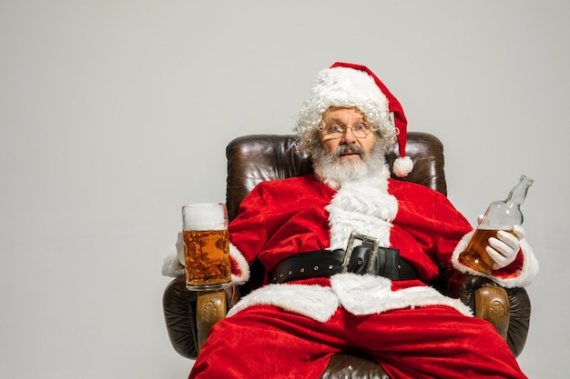 Santa Claus tirando de una enorme bolsa llena de regalos de Navidad aislado sobre fondo blanco.