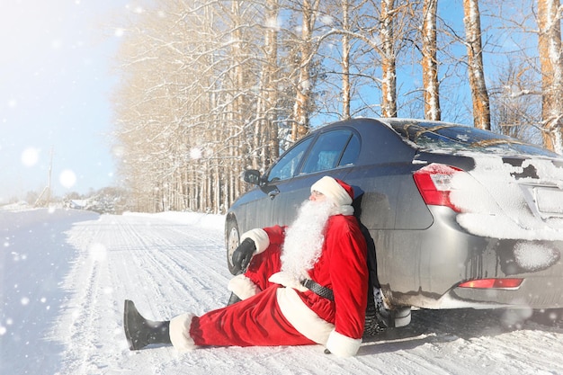 Santa Claus viene con regalos del exterior. Santa con un traje rojo con barba y gafas está caminando por el camino hacia la Navidad. Papá Noel trae regalos a los niños.