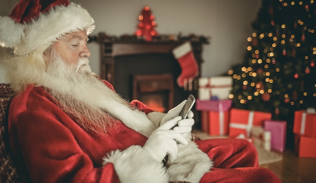 Santa concentrado con smartphone en Navidad