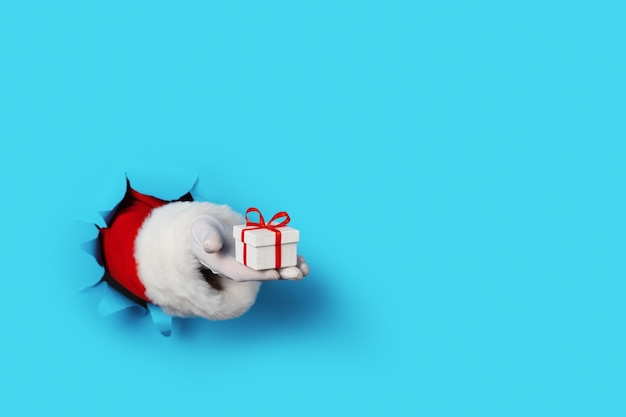 Santa Holding Small Gift Box in seiner Hand isoliert über hellblau - nur Hand und Arm