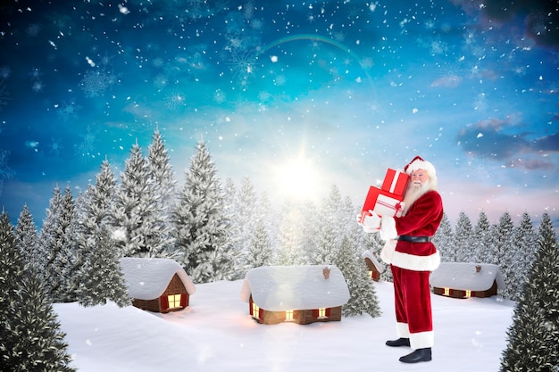 Santa lleva algunos regalos contra el pueblo cubierto de nieve en el bosque